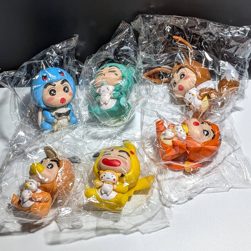 Six Packaged Figures of Shin Chan Dressed in pokemon Onisies, Pikachu Eevee Psyduck Squirtle Charmander Bulbasaur, on a black and white background