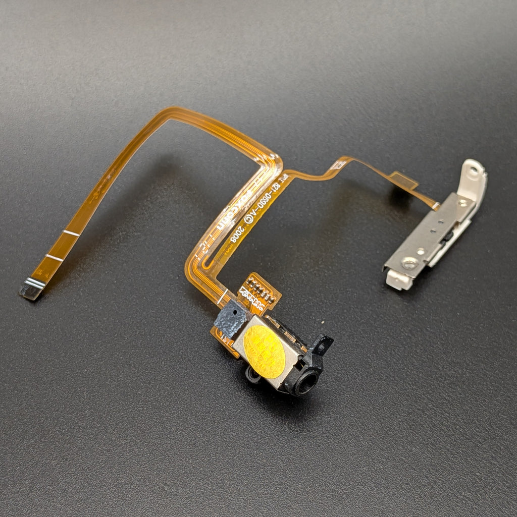 A replacement iPod flex cable assembly with a gold ribbon cable, an audio jack, and a silver metal connector, shown on a dark gray textured background.
