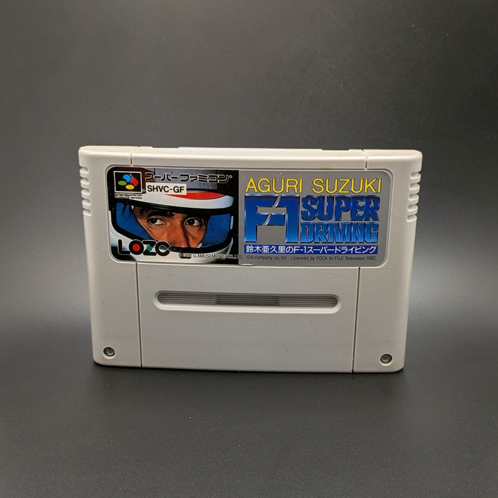 Aguri Suzuki F-1 Super Driving video game cartridge for Nintendo's Super Famicom (SFC) Entertainment System, shown standing up and facing forward on a dark grey background.
