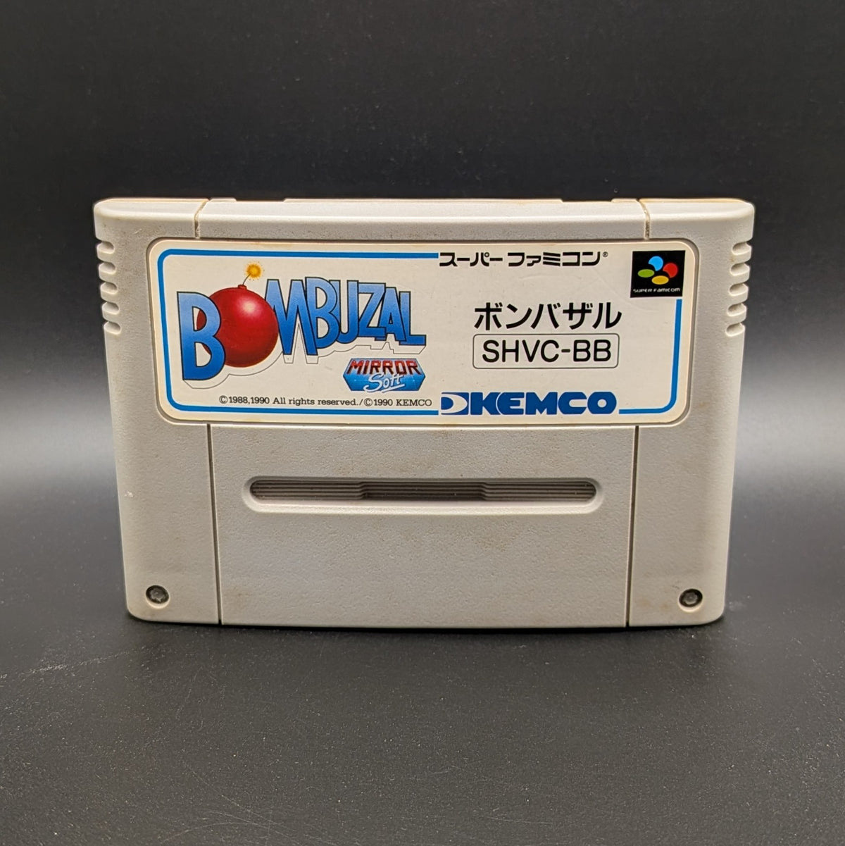Bombuzal video game cartridge for Nintendo's Super Famicom (SFC) Entertainment System, shown standing up and facing forward on a dark grey background.