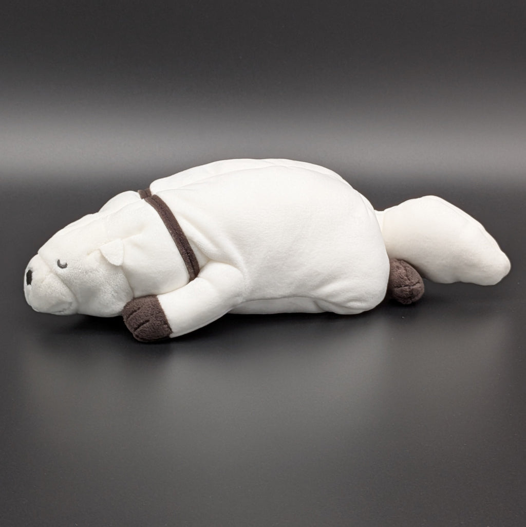 A plush Bond Forger dog toy shown lying on its belly, facing side on. Sitting on a dark grey surface, with soft white fur and brownish grey accents on its paws, snout, and collar. From the anime/manga series Spy X Family, made by Club Mochi-Mochi.