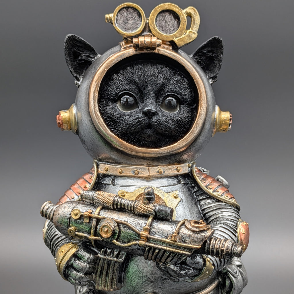 A black cat dressed as a retro sci-fi space explorer in a detailed metallic spacesuit with gold goggles and a gun, set against a solid gray background.