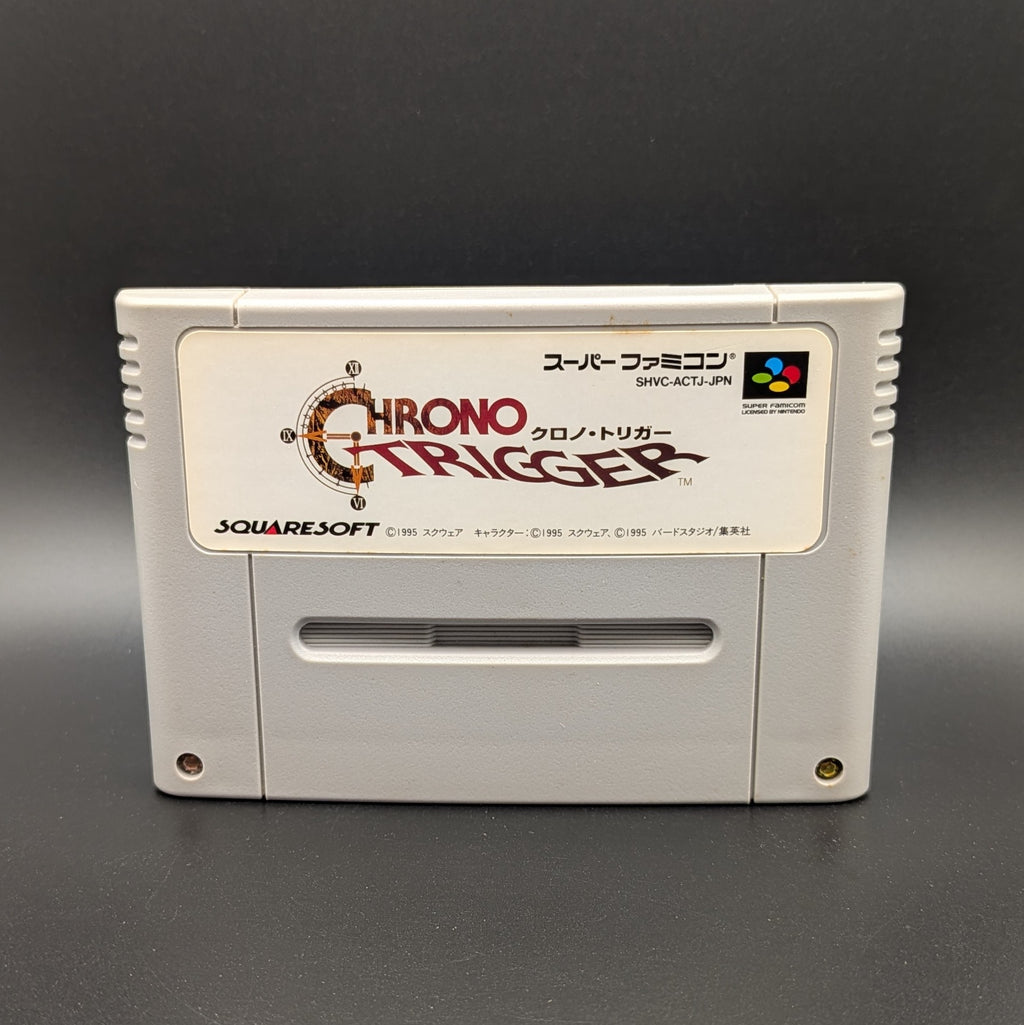 Chrono Trigger video game cartridge for Nintendo's Super Famicom (SFC) Entertainment System, shown standing up and facing forward on a dark grey background.
