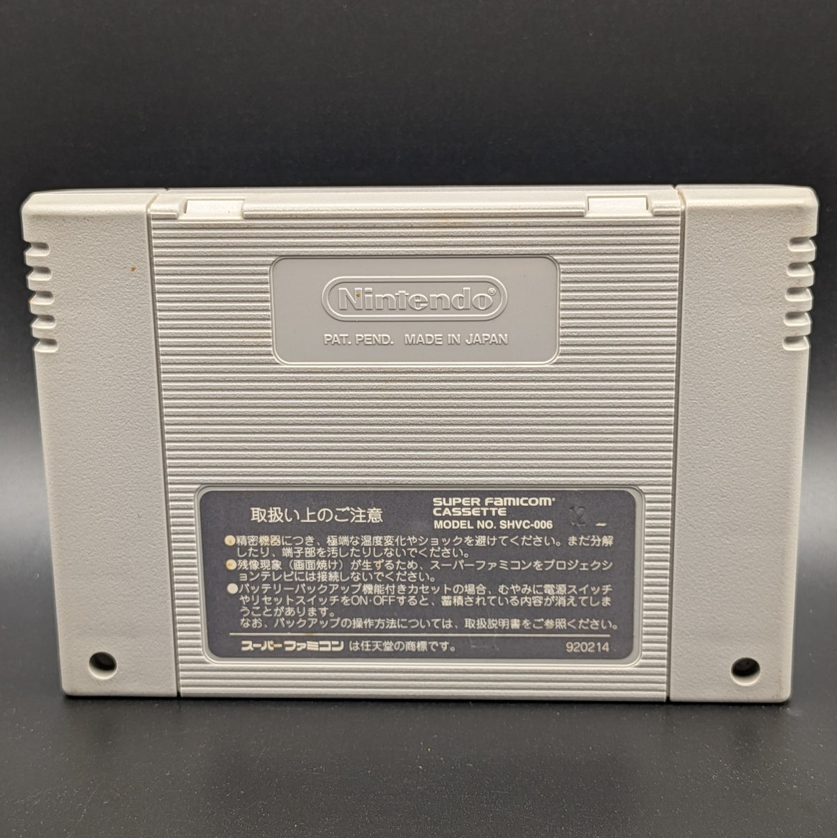 Chrono Trigger video game cartridge for Nintendo's Super Famicom (SFC) Entertainment System, showing the back of the cartridge. It sits on a dark grey background.

