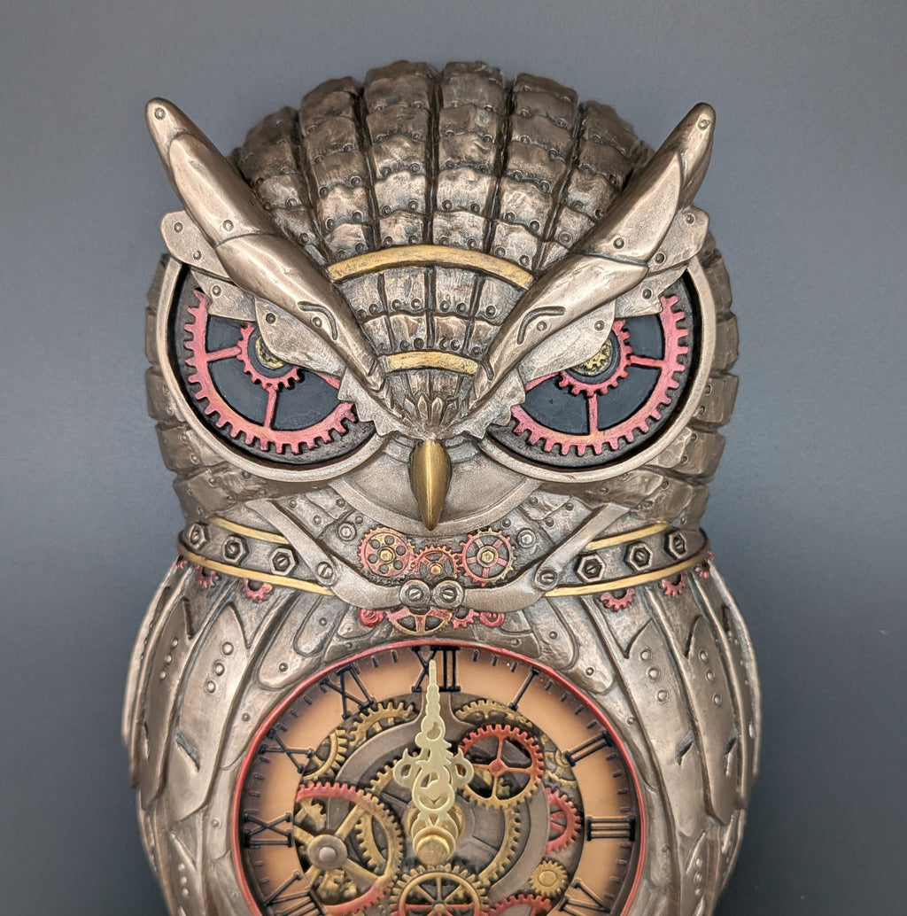 Steampunk owl wall clock with intricate gears, silver-toned feathers, and red accents, shown against a solid gray background.