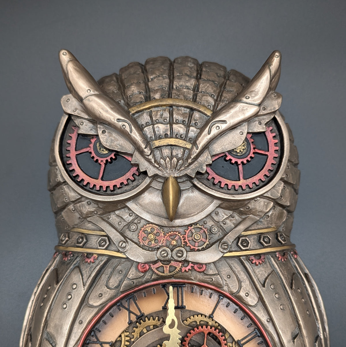 Steampunk owl clock with intricate gears, rivets, and clock face details, photographed against a solid dark gray background.