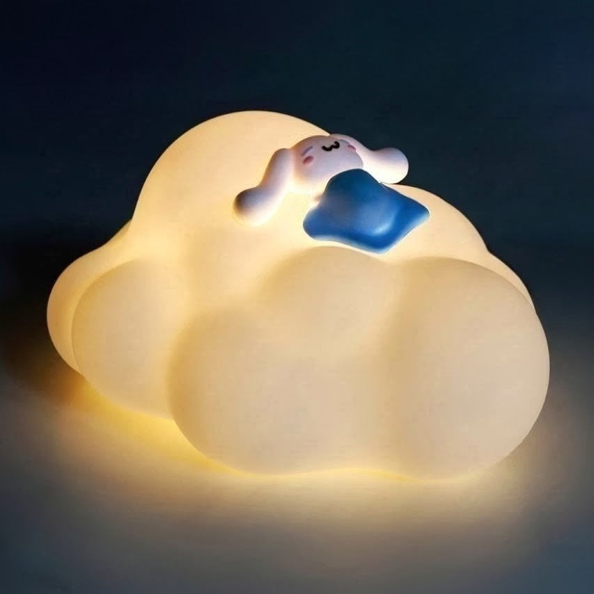 A glowing cloud-shaped night light with a small sleeping character resting on top, set against a dark background.
