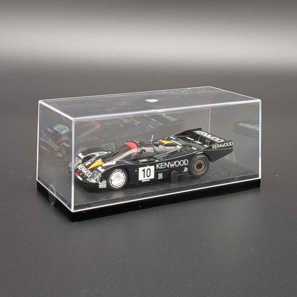 A black Kenwood race car model displayed inside a clear acrylic display case on a dark gray surface.