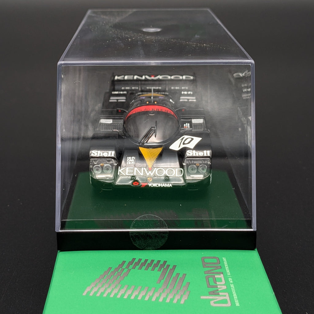 A miniature Kenwood 24 Hours of Le Mans race car model inside a clear plastic display case, with a green dnano branded card placed in front on a black background.