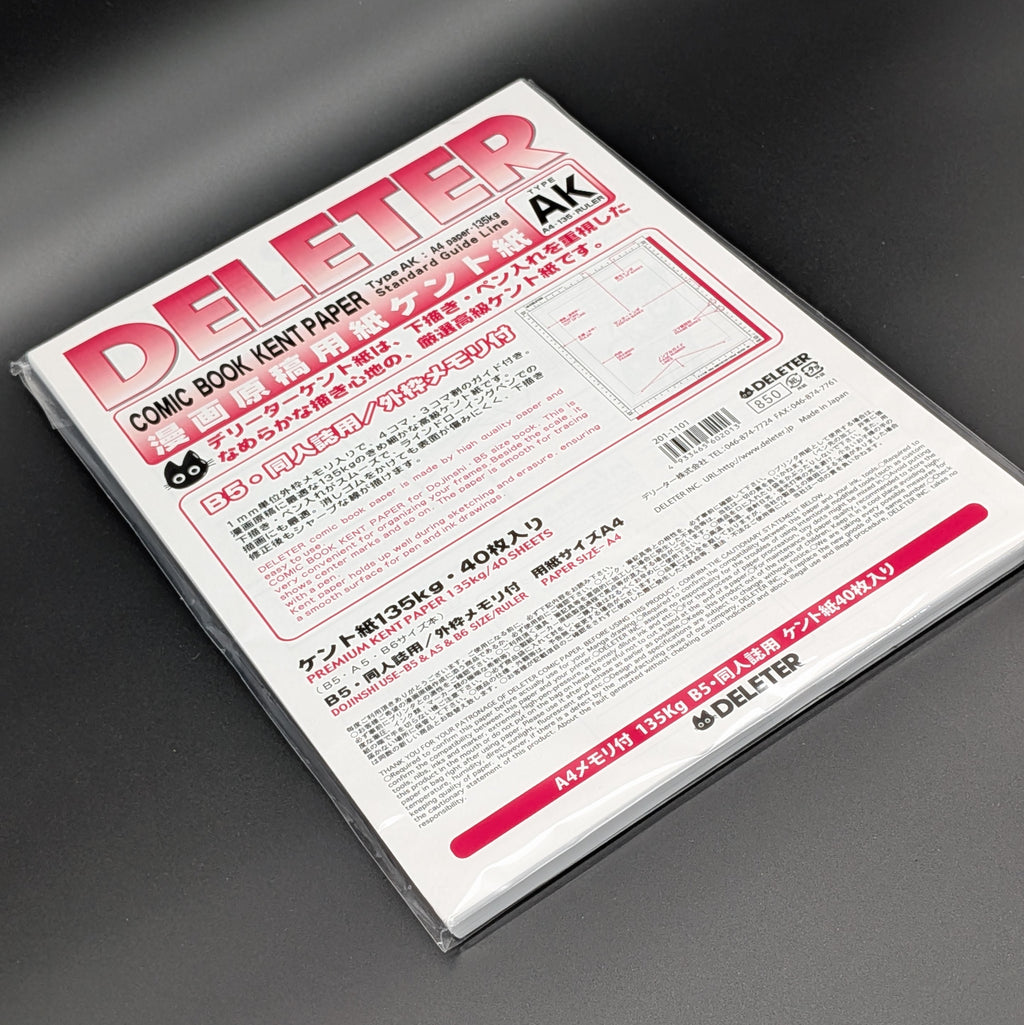 A sealed package of Deliter Comic Book Kent Paper, Type AK, containing 40 sheets of 135g premium paper. The packaging is white with bold pink and black text, the paper is leaning dramatically to the left and photographed on a grey background.