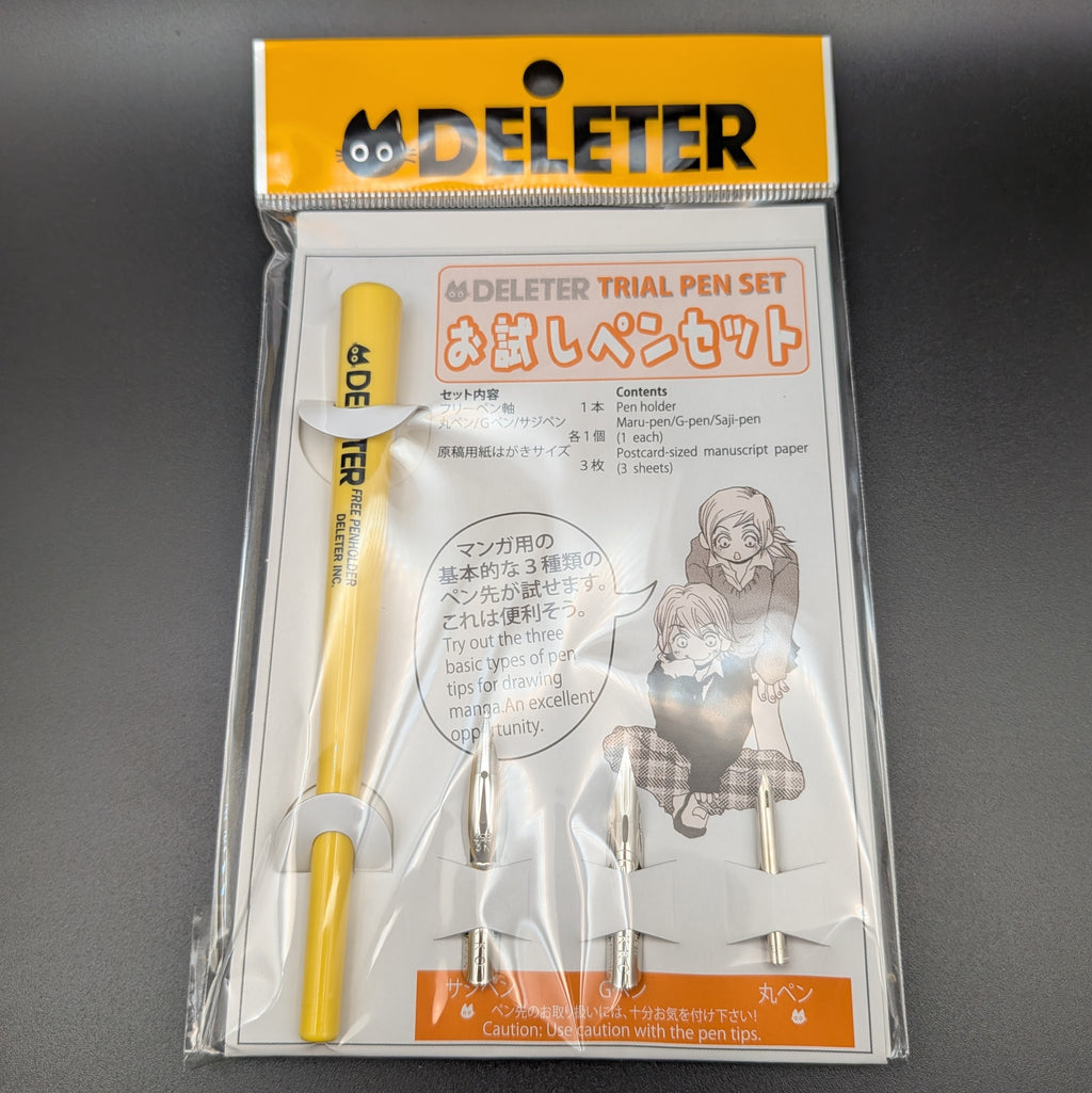 DELETER Trial Pen Set in its original retail packaging, featuring a yellow pen, 3 pen nibs, manuscript paper, with a white and orange card insert. A close up image, taken on a black background.