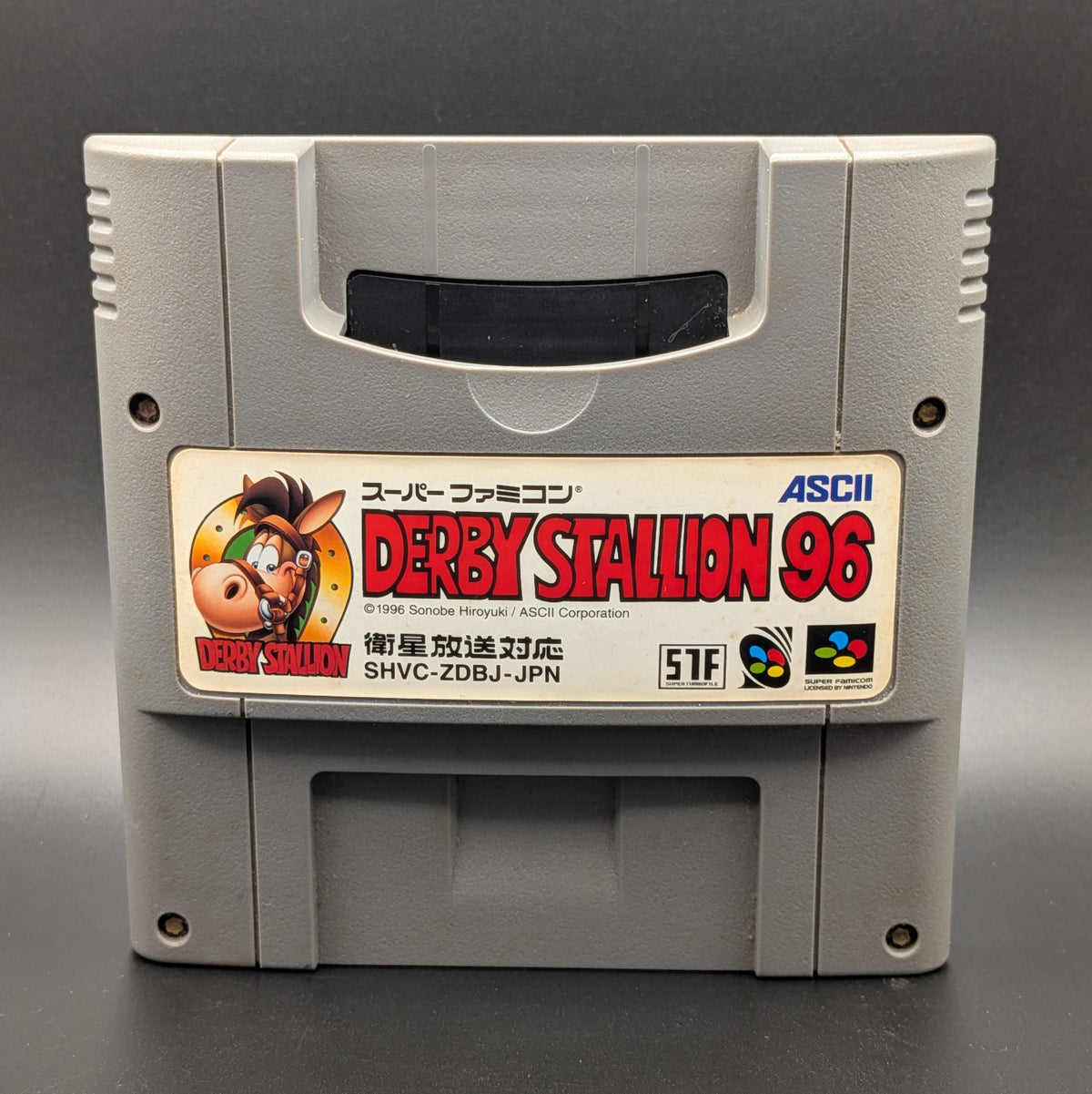 Derby Stallion 96 video game cartridge for Nintendo's Super Famicom (SFC) Entertainment System, shown standing up and facing forward on a dark grey background.
