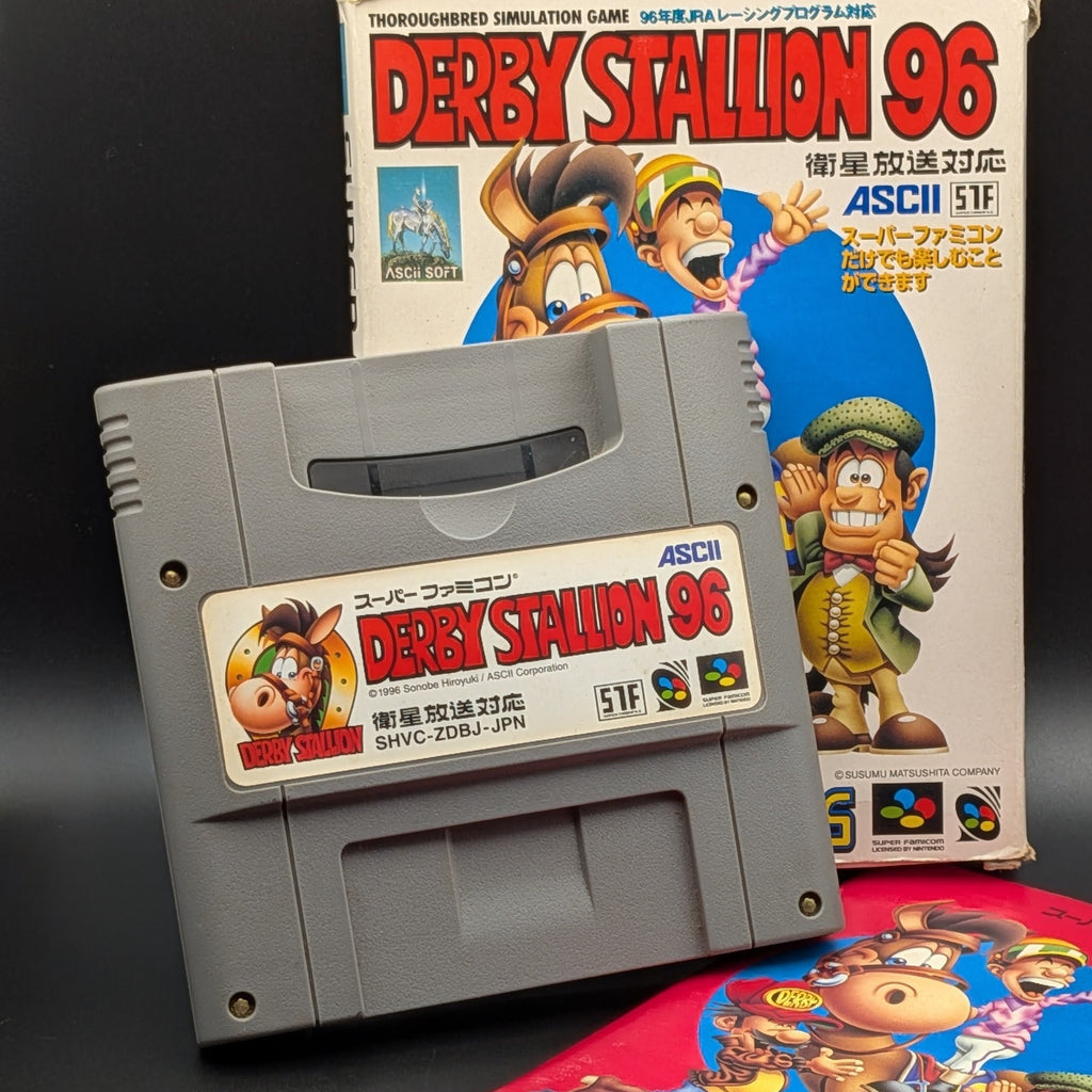 A close up of Derby Stallion 96 video game cartridge for Nintendo's Super Famicom (SFC) Entertainment System, shown standing up, in front of its box and the manual peaking out from beneath the two. Displayed on a dark grey background.
