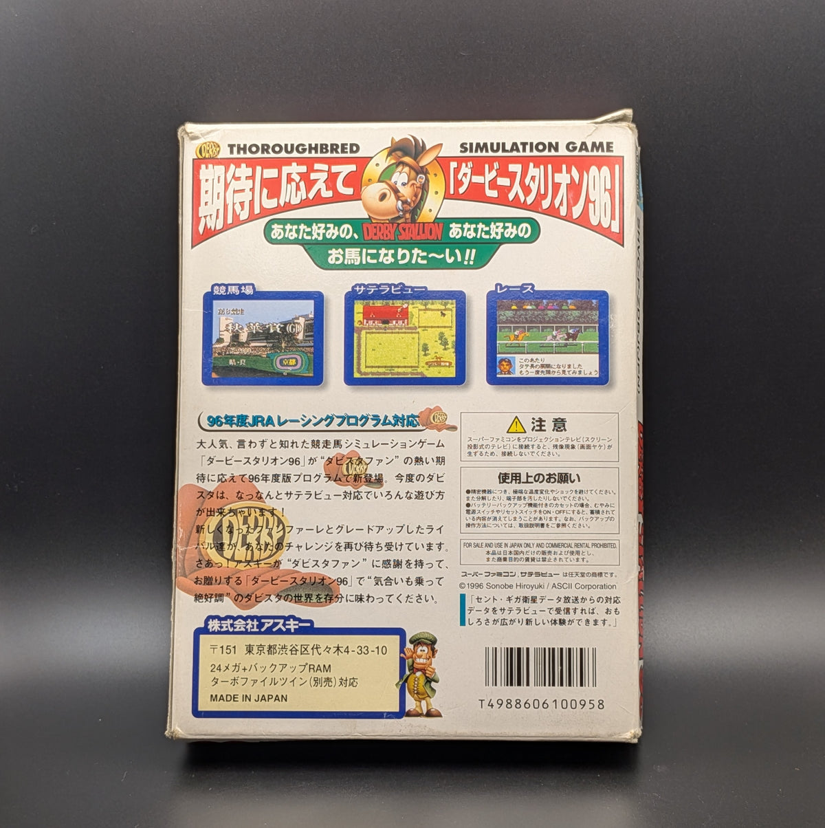 Derby Stallion 96 boxed, a video game for Nintendo's Super Famicom (SFC) Entertainment System, shown standing up to reveal the back of the box where you can see images of game-play and information in Japanese. Pictured on a dark grey background. Slight wear and tear at the edges form age.
