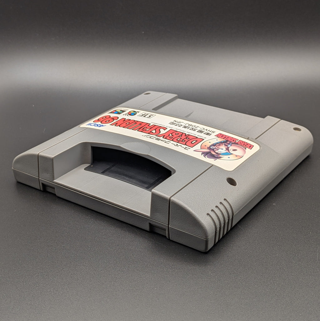 Derby Stallion 96 video game cartridge for Nintendo's Super Famicom (SFC) Entertainment System, shown laying on its back with the label facing upwards. Showing the left hand side and top section. It sits on a dark grey background.