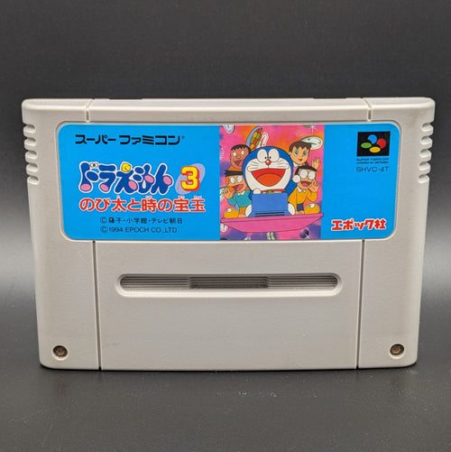 A close up of Doraemon 3 video game cartridge for Nintendo's Super Famicom (SFC) Entertainment System, shown standing up and facing forwards on a dark grey background.