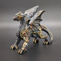 A steampunk-style fantasy dragon figurine with metallic gray scales, gold gears, and copper-toned mechanical details, photographed on a dark gray studio background.