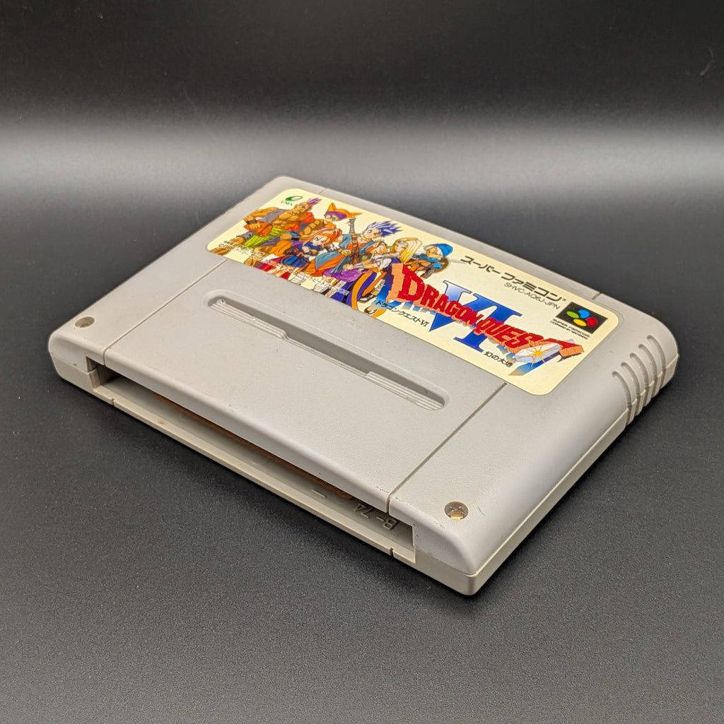 Dragon Quest VI video game cartridge for Nintendo's Super Famicom (SFC) Entertainment System, shown laying on its back with the label facing upwards. Showing the right hand side and bottom slot. It sits on a dark grey background