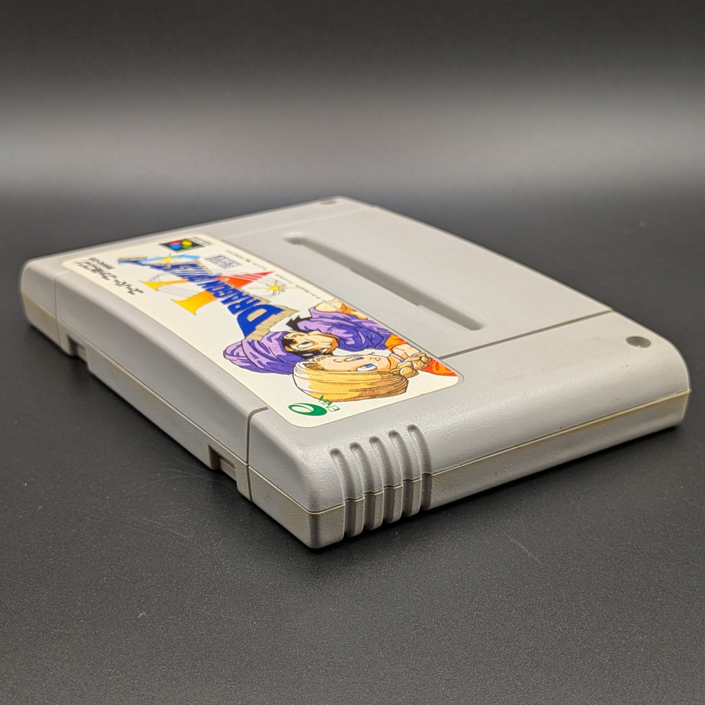 Dragon Quest V video game cartridge for Nintendo's Super Famicom (SFC) Entertainment System, shown laying on its back with the label facing upwards. Showing the left hand side and top edge. It sits on a dark grey background.