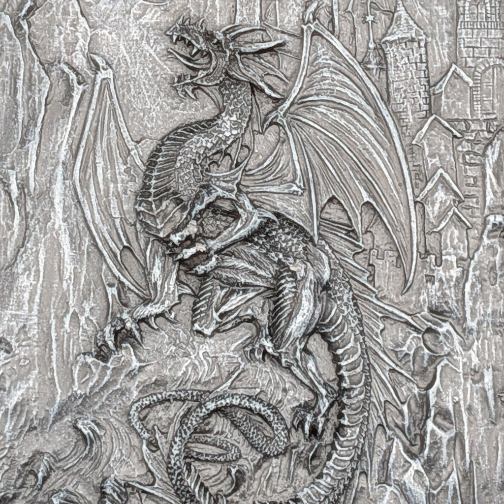 A close-up of a resin cast featuring a detailed dragon with spread wings and a castle in the background.
