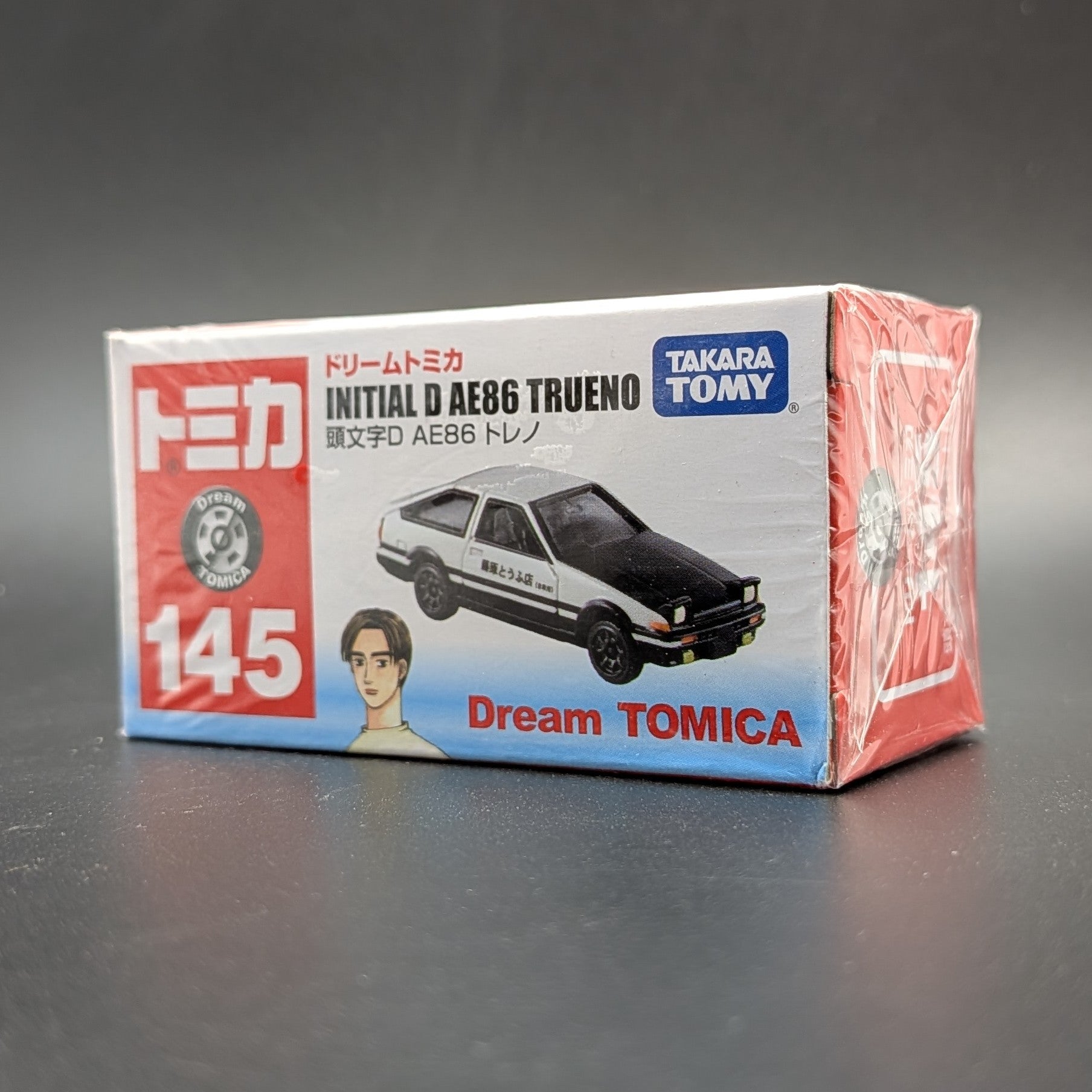 DreamTomica #145 AE86 Trueno from Intial D. Box facing forwards at a 3/4 view on a grey background.