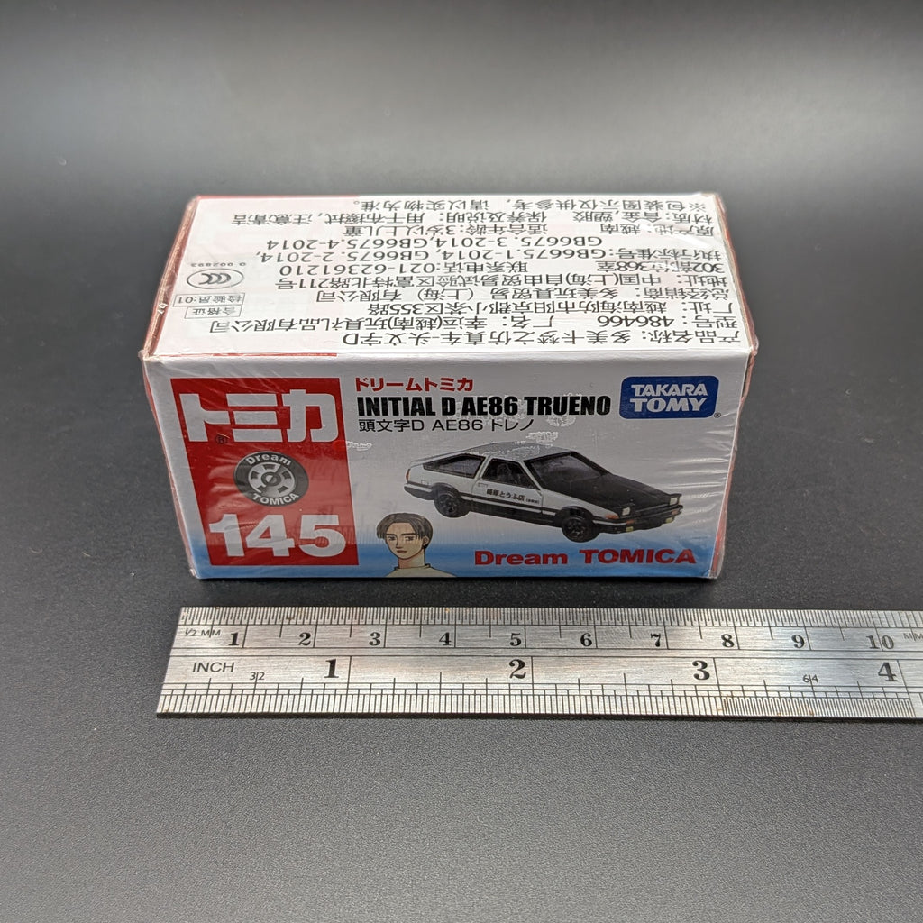 DreamTomica #145 AE86 Trueno from Intial D. Box facing forwards straight on, with a metal ruler, on a grey background.