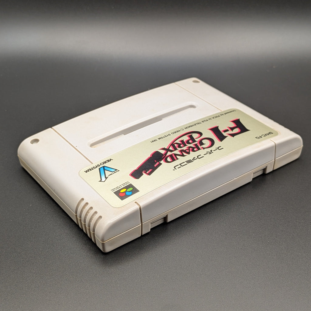 F-1 Grand Prix video game cartridge for Nintendo's Super Famicom (SFC) Entertainment System, shown laying on its back with the label facing upwards. Showing the right hand side and top edge. It sits on a dark grey background