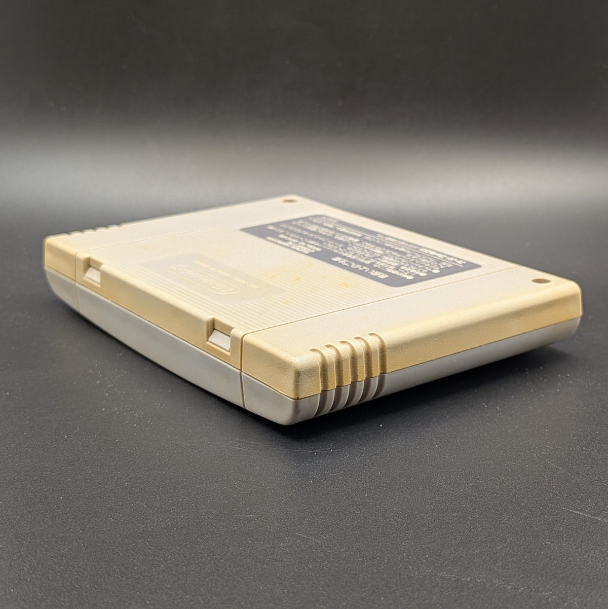 F-1 Grand Prix video game cartridge for Nintendo's Super Famicom (SFC) Entertainment System, shown from an angled top-down view on a dark grey background. You can see yellowing on the back panel.