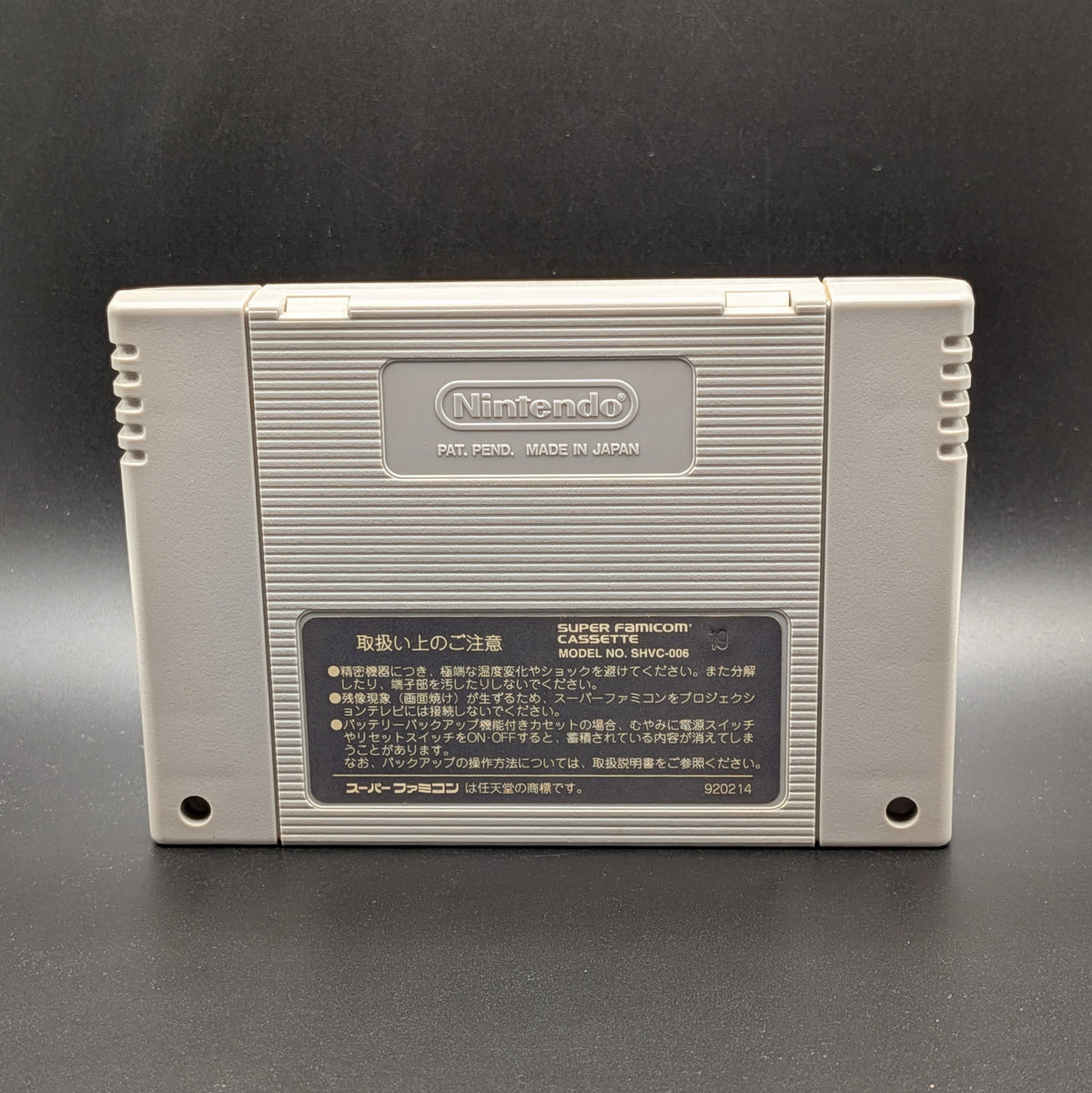 The back of a classic Nintendo Game Boy cartridge, Gindama Oyakata no Jissen Pachinko, manufactured by Super Nintendo. The light gray plastic cartridge features the embossed Nintendo logo on the upper back and a black label with Japanese text and product details on the lower back, set against a dark grey background.