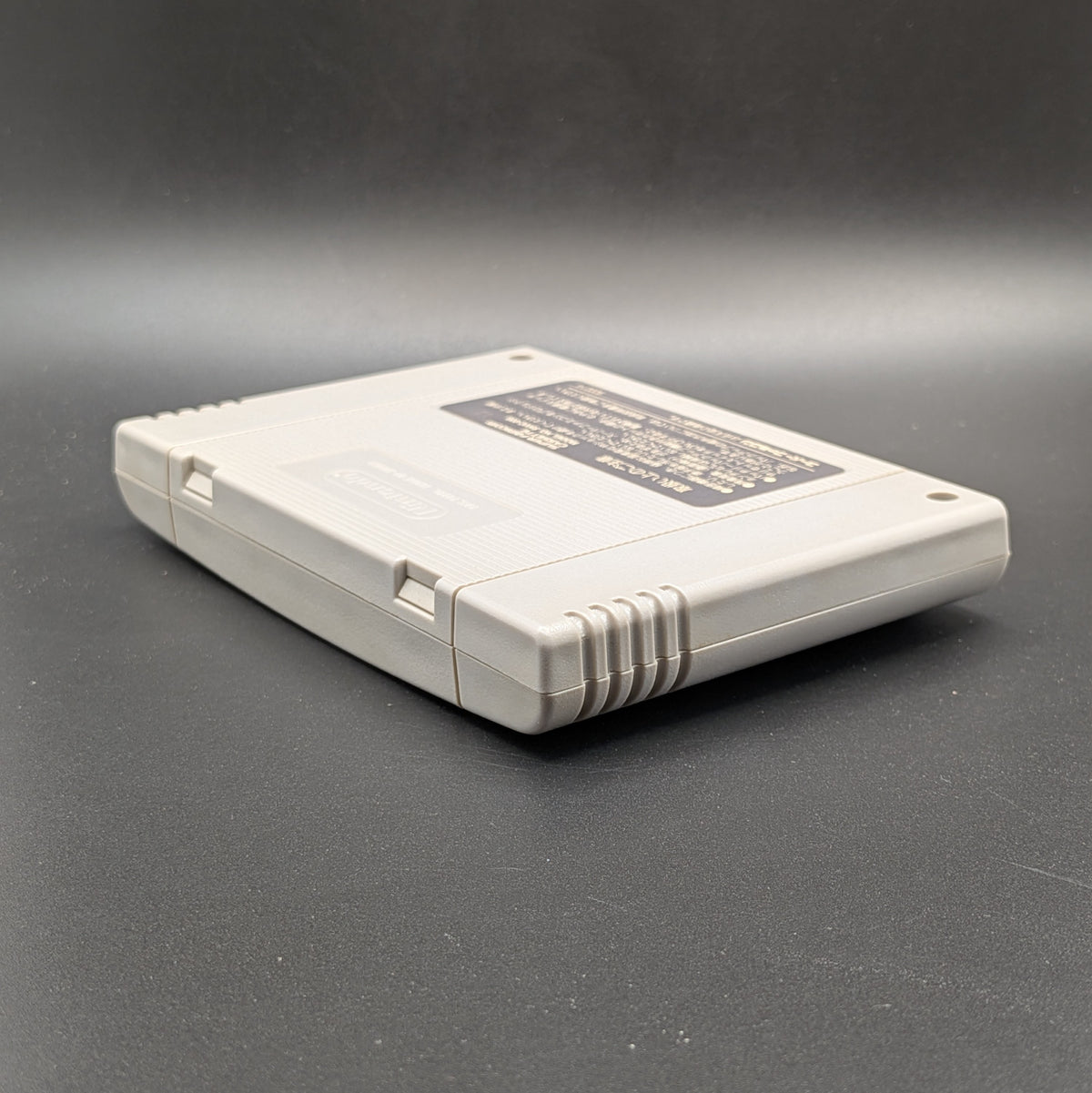 Gindama Oyakata no Jissen Pachinko video game cartridge for Nintendo's Super Famicom (SFC) Entertainment System, shown laying on its front, showing the back label and Nintendo stampped on the back, on a dark grey background.
