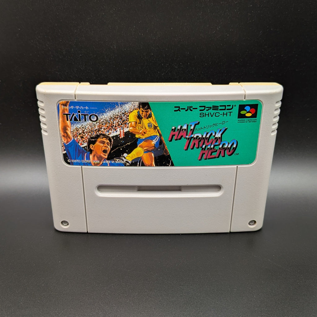 Hat Trick Hero video game cartridge for Nintendo's Super Famicom (SFC) Entertainment System, shown standing up and facing forwards on a dark grey background.