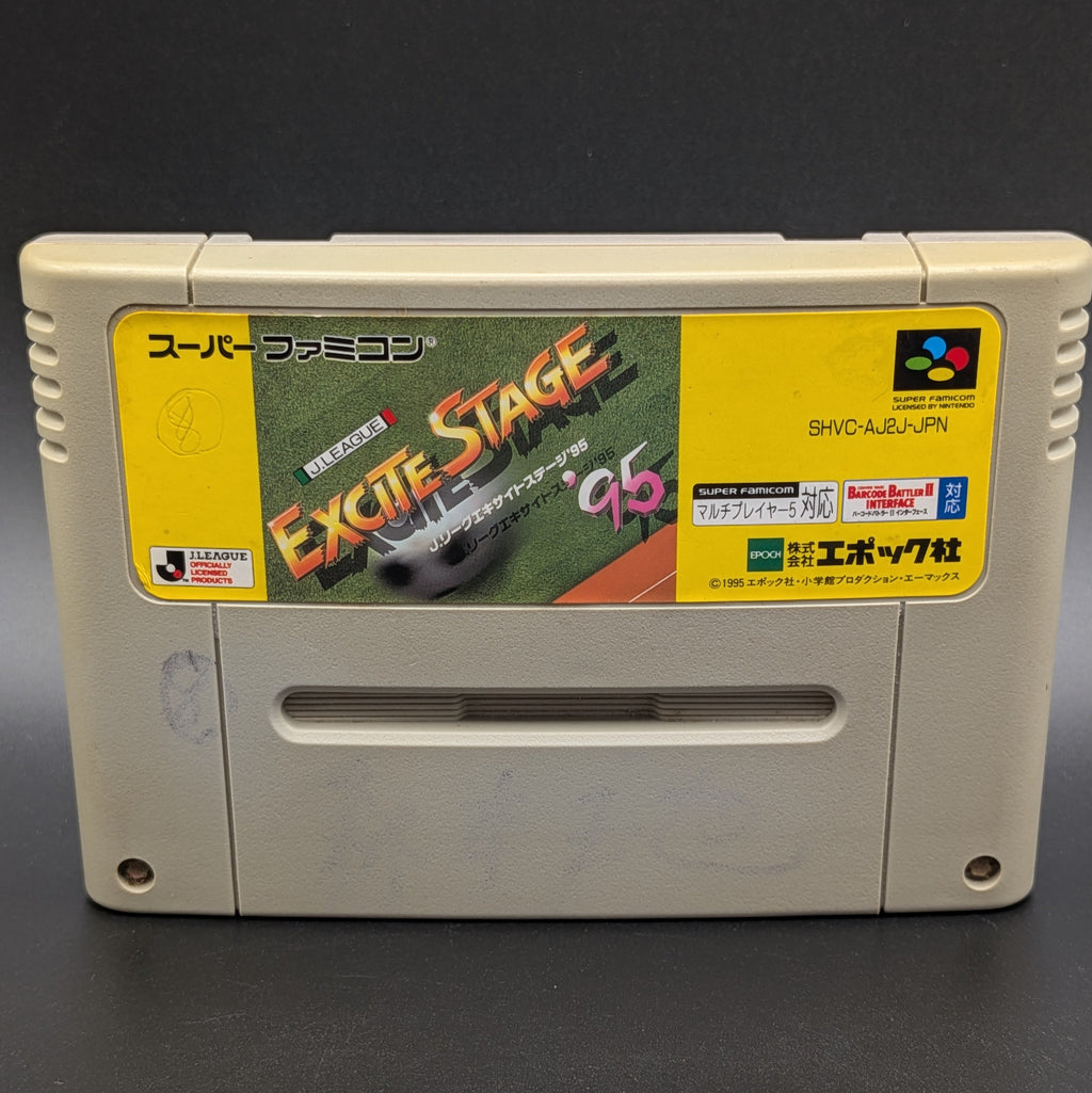 A close up of J League Excite Stage '95 video game cartridge for Nintendo's Super Famicom (SFC) Entertainment System, shown standing up and facing forward on a dark grey background.