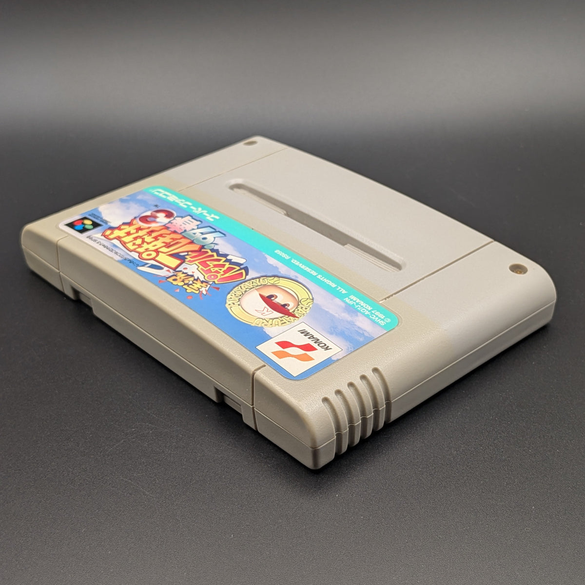 Jikkyou Powerful Pro Yakyuu 3 '97 video game cartridge for Nintendo's Super Famicom (SFC) Entertainment System, shown laying on its back with the label facing upwards. Showing the left hand side and top edge. It sits on a dark grey background 