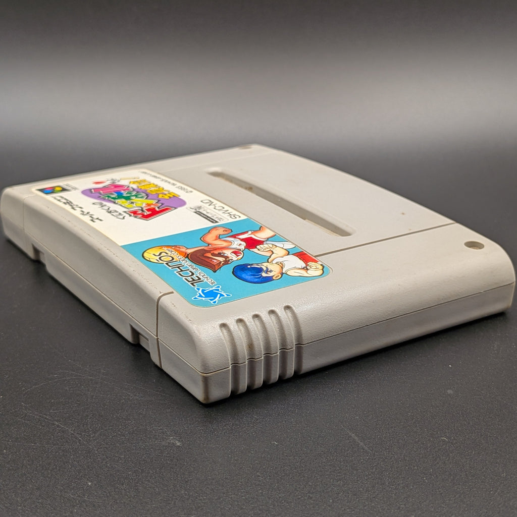 Kunio-Kun no Dodgeball video game cartridge for Nintendo's Super Famicom (SFC) Entertainment System, shown laying on its back with the label facing upwards. Showing the left hand side and top edge. It sits on a dark grey background