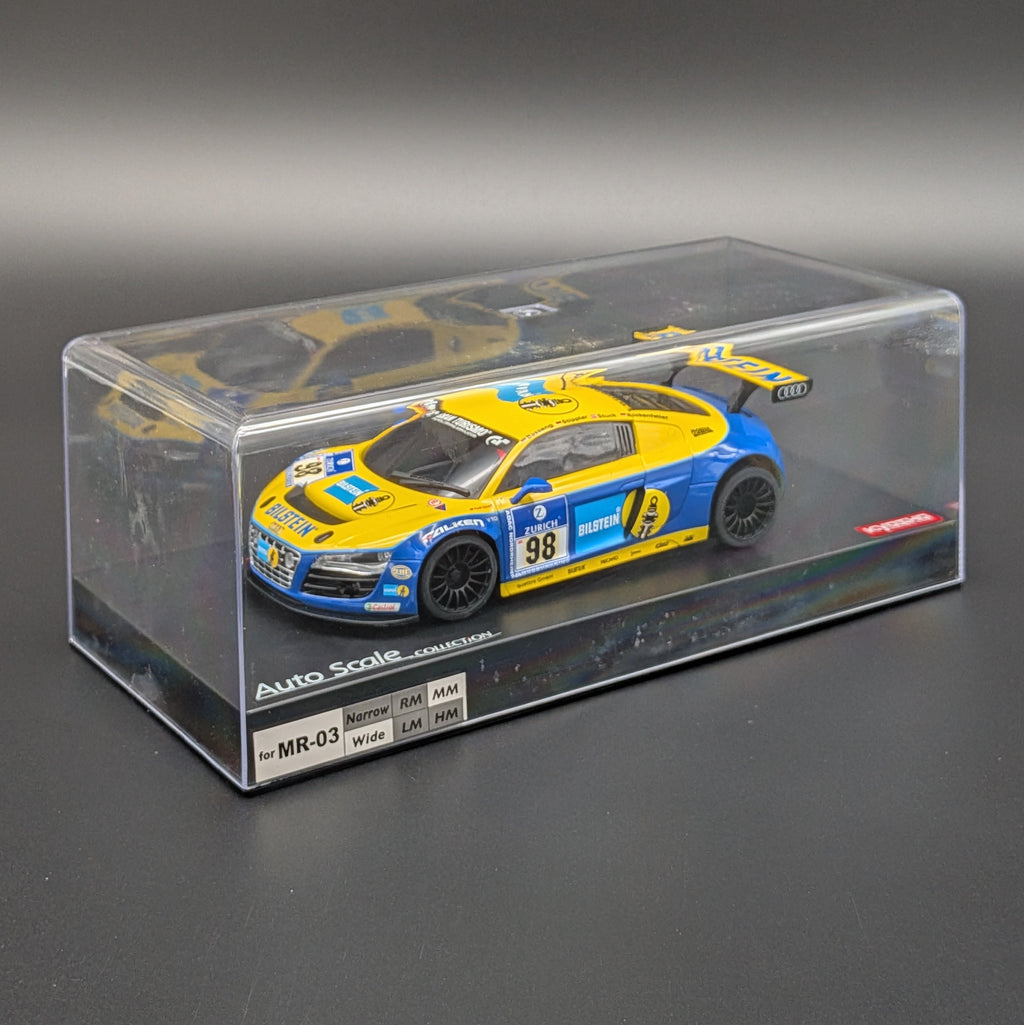 A die-cast model car in a clear display box. The car is yellow and blue with racing decals, number 98, and sponsor logos including Audi and Castore.