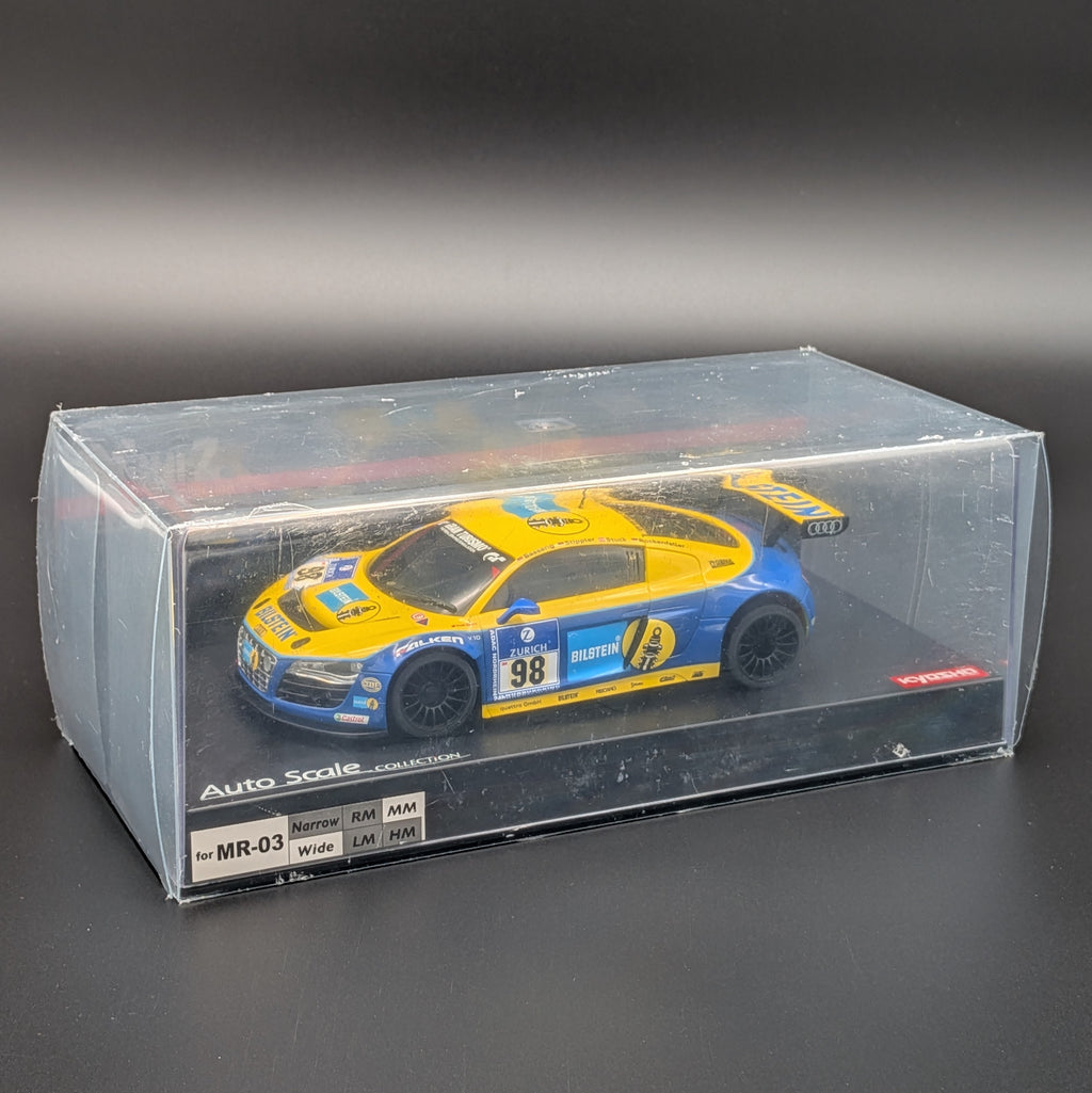 A 1:27 scale model car of a blue and yellow Audi R8 Phoenix Racing LMS race car, displayed inside its clear plastic display box on a dark gray background.