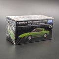 A boxed Tomica Mazda Savanna RX-7 model car, still wrapped in clear plastic, on a dark gray background. The box shows a green sports car and the text 'tomica', 'MAZDA SAVANNA RX-7 (SA22C)', and 'TAKARA TOMY'.