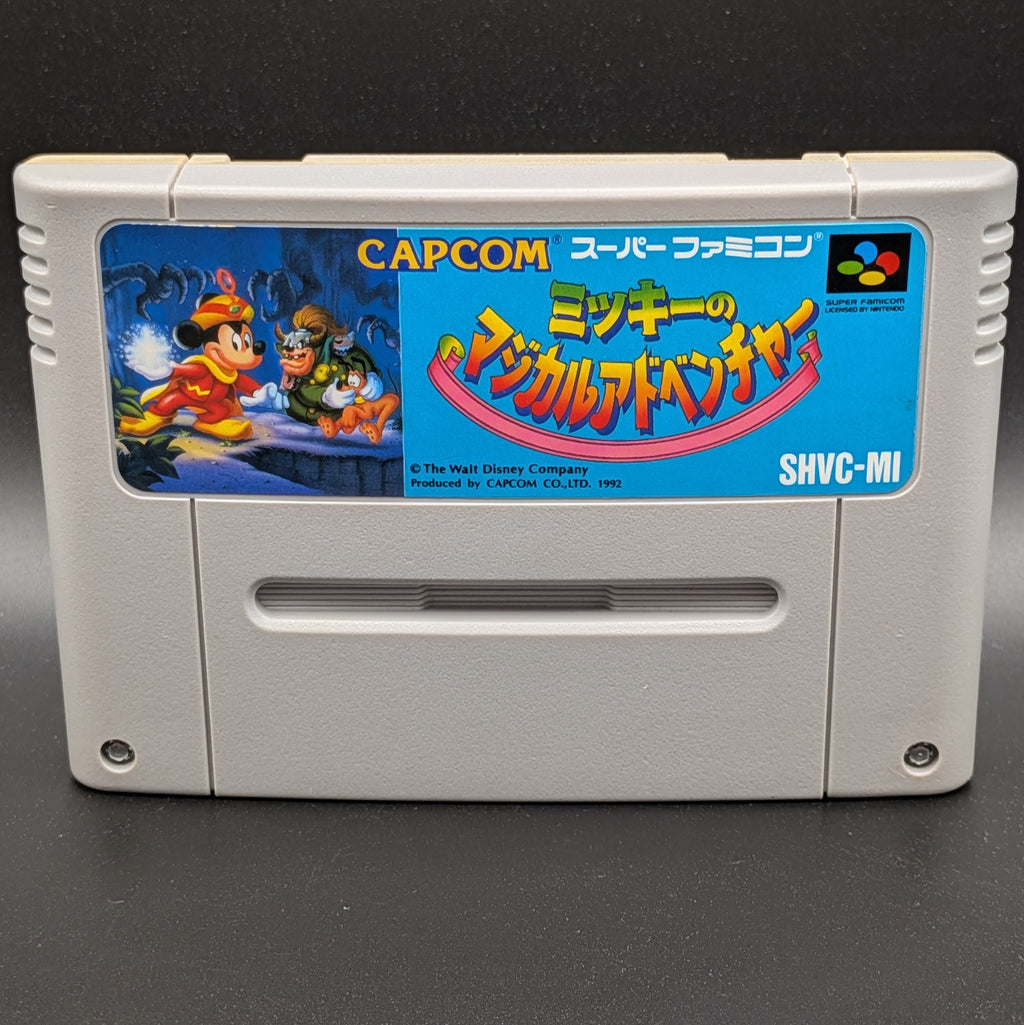 A close up of Mickey's Magical Adventure video game cartridge for Nintendo's Super Famicom (SFC) Entertainment System, shown standing up and facing forwards on a dark grey background.
