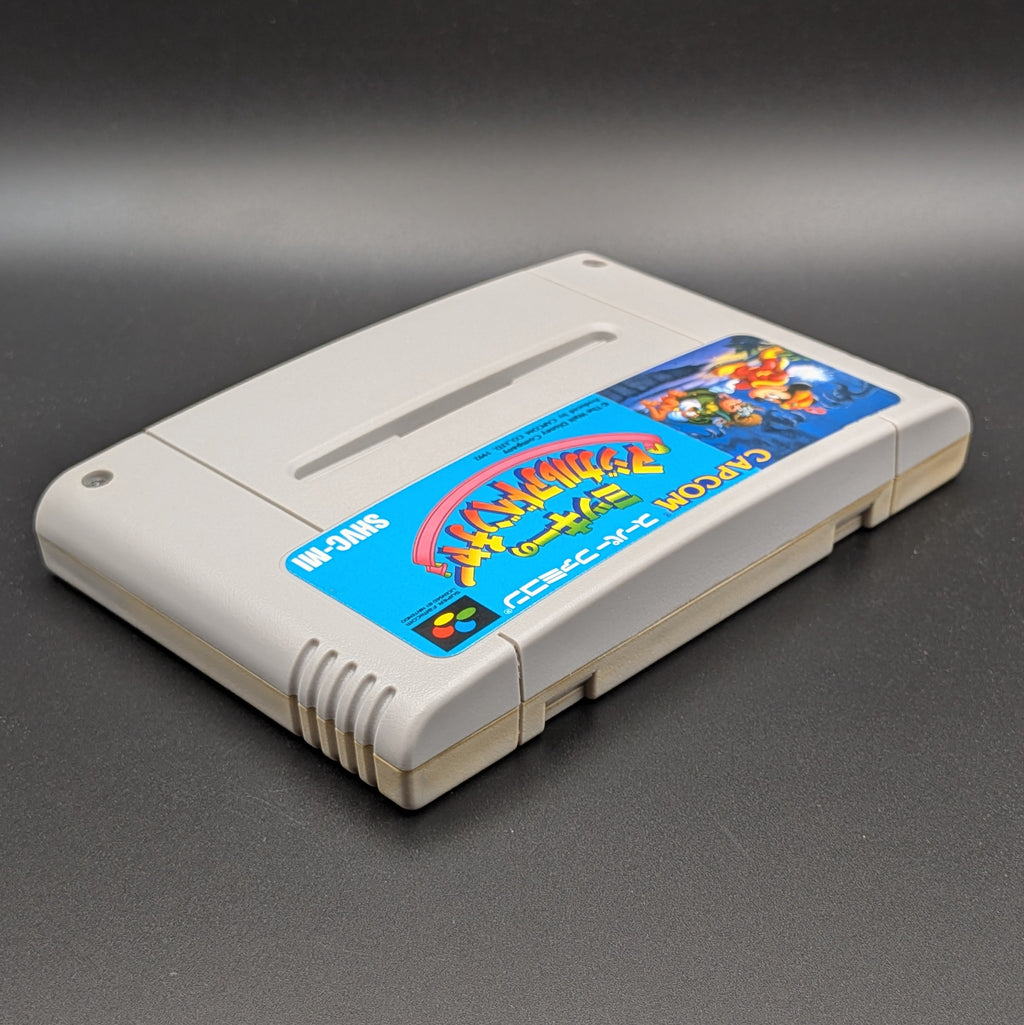 Mickey's Magical Adventure video game cartridge for Nintendo's Super Famicom (SFC) Entertainment System, shown laying on its back with the label facing upwards. Showing the right hand side and top edge. It is displayed on a dark grey background.