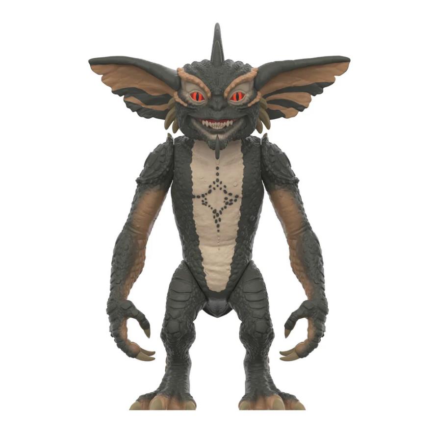A Gremlins toy figure of the main creature, standing upright on a plain white background. The figure has dark gray and brown textured skin, large bat-like ears, red eyes, and a cream-colored chest panel with a black star-like pattern.