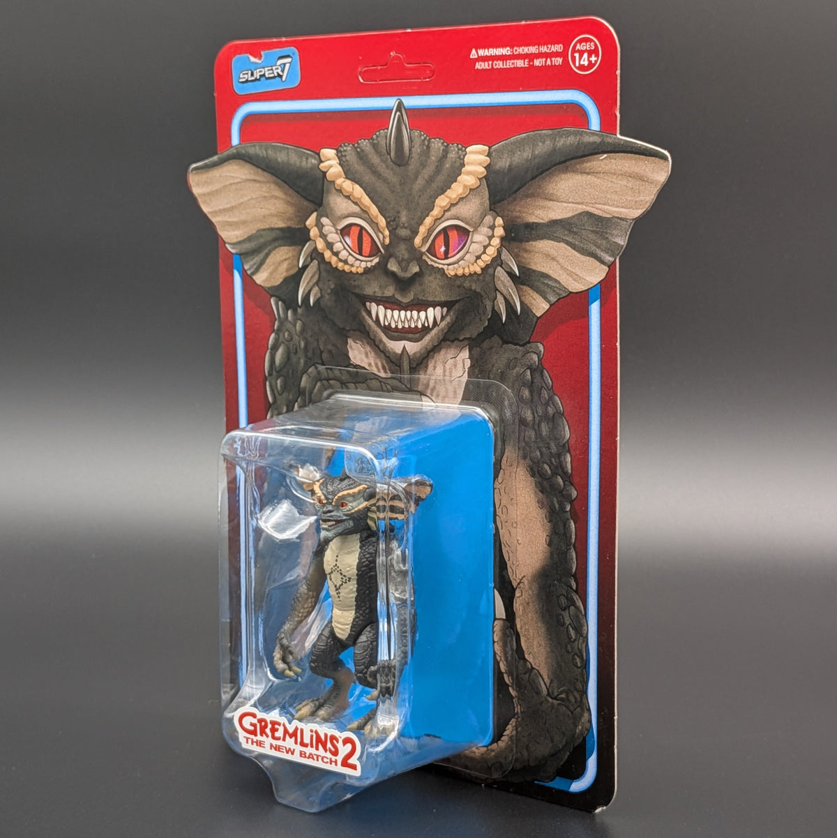Super7 Gremlins 2 action figure in its original blister card packaging, featuring a detailed illustration of the creature on the backing card.