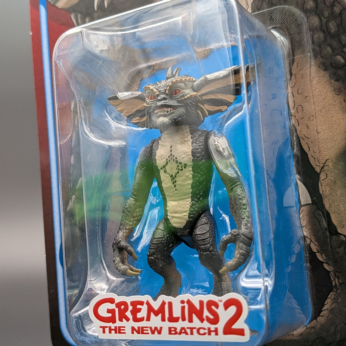 Gremlins 2: The New Batch action figure of a gremlin in its original blister packaging, featuring green, gray, and beige colors with red eyes.