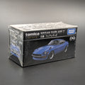 A boxed Tomica Nissan Fairlady Z model car package, sealed in clear plastic, photographed on a dark gray surface against a gray background. The box is black with white text and shows a blue car illustration, with visible brands Tomica and Takara Toy.