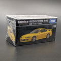 A boxed Tomica Nissan Silvia (S15) model car set, still wrapped in clear plastic, on a dark gray surface. The box is black with white text and shows a yellow car graphic, with the Takara Tomy logo in the top right.