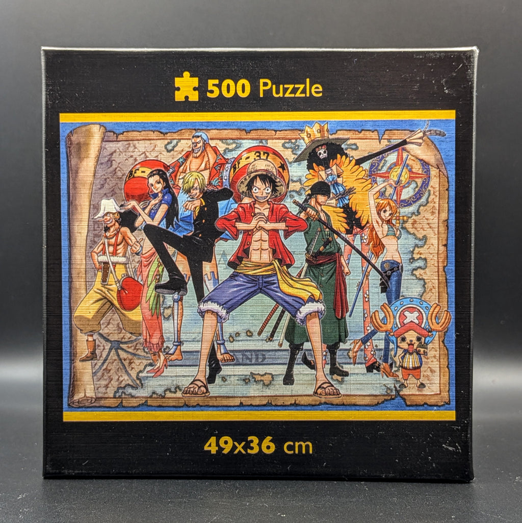 One Piece Straw Hat Crew 500pc puzzle still sealed in Clementoni's signature square box. The box features a detailed, colourful illustration of Luffy, Nami, Zoro and the crew. Showing the finished puzzle image when complete, displayed on a dark grey background.