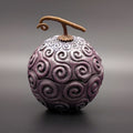 A resin trinket box of the Devil Fruit from the anime One Piece, featuring a textured purple body with swirling patterns and a brown stem, set against a dark grey gradient background.