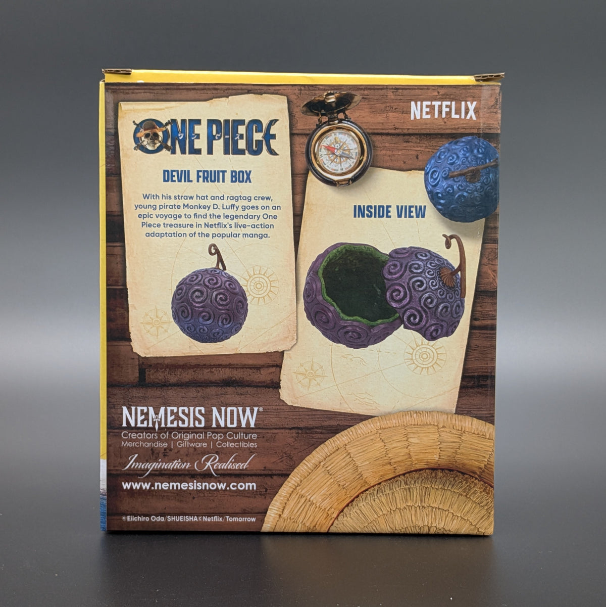 The retail packaging box for the Netflix adaptation of One Piece, of the Devil Fruit trinket box with images showing it both closed and open, set against a dark grey background. Manufactured by Nemesis Now.