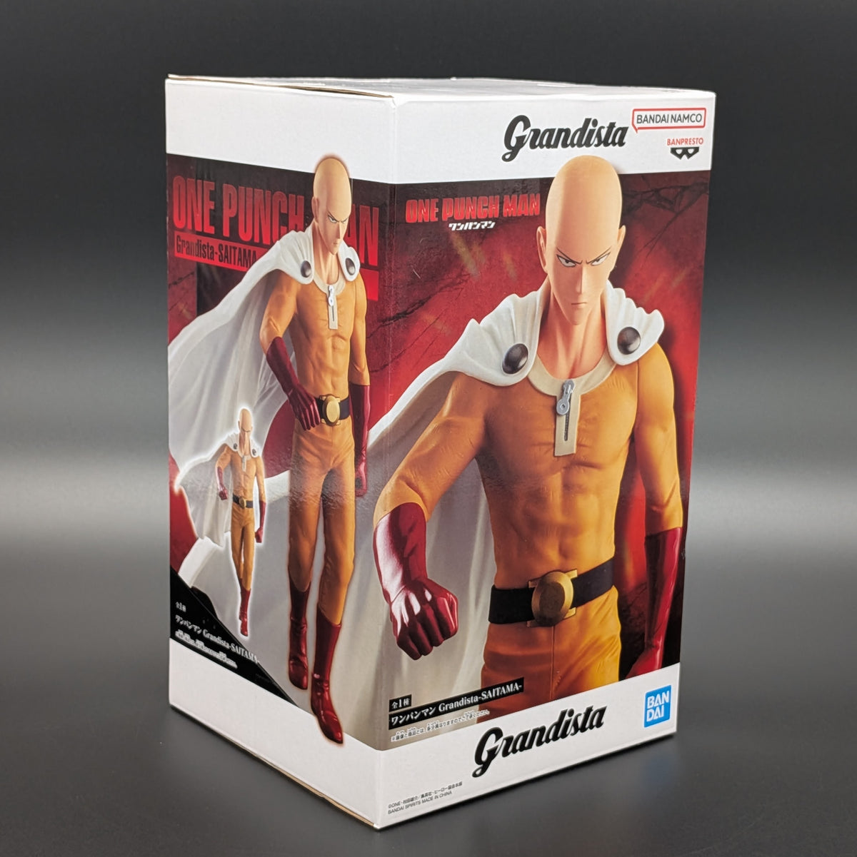 Bandai Namco Granddista One Punch Man Saitama 1/12 scale collectible figure  in box, featuring character artwork of Saitama in his signature orange and white outfit.