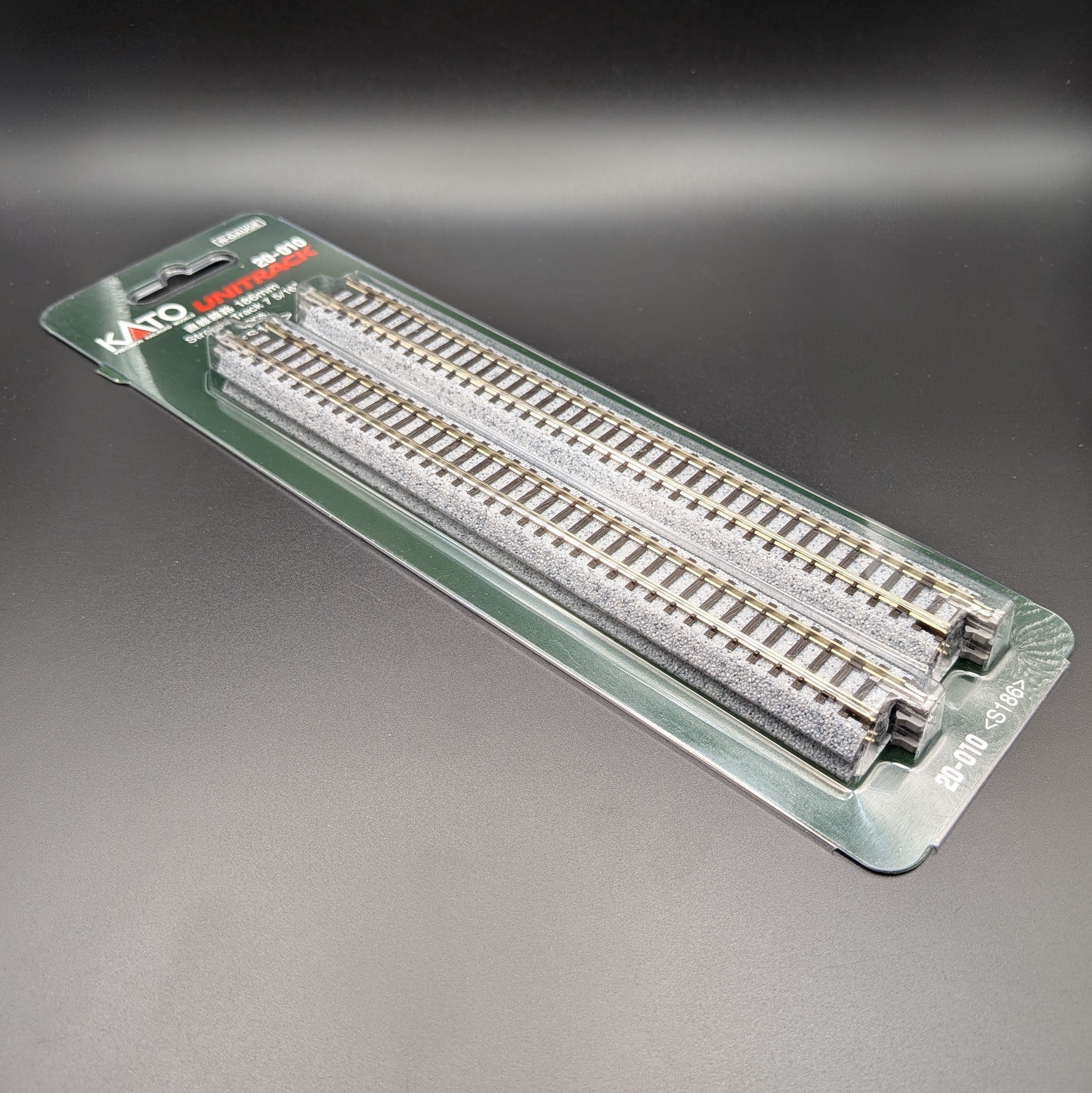 Kato Unitrack 20-010 S186 — Straight Track, N-gauge (Pack of 4). Item is shown laying down on a black background at a 3/4, view giving view of the sides of the track.