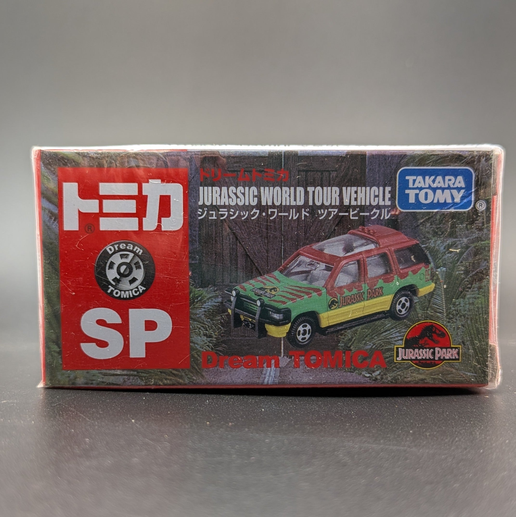 Takara Tomy Dream Tomica SP Jurassic World Tour Vehicle (Ford Explorer), 1/64 scale diecast boxed and unopened. Facing the image straight on and displayed on a black background.